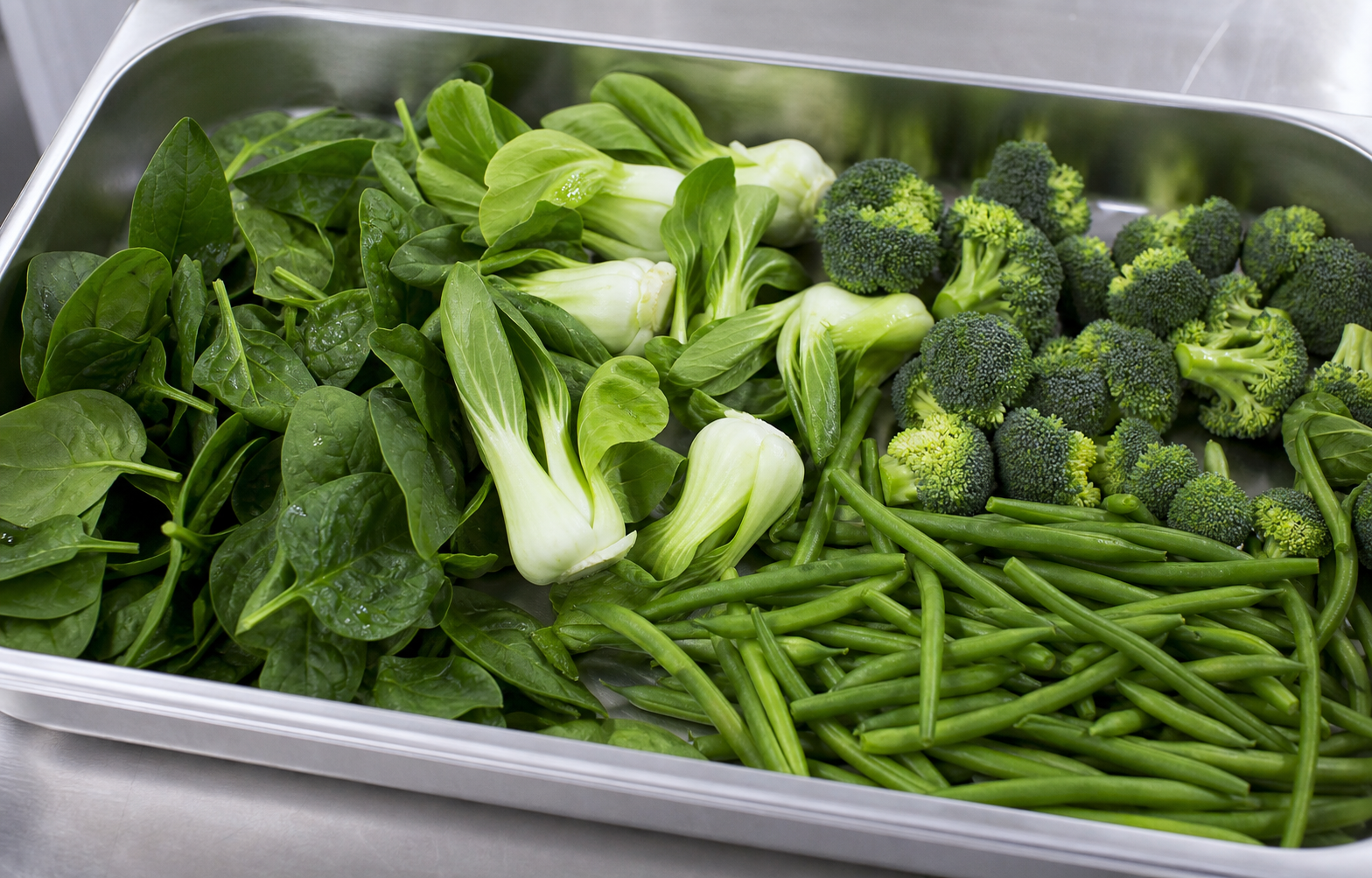 Leafy vegetables prepared for blanching in food-grade trays